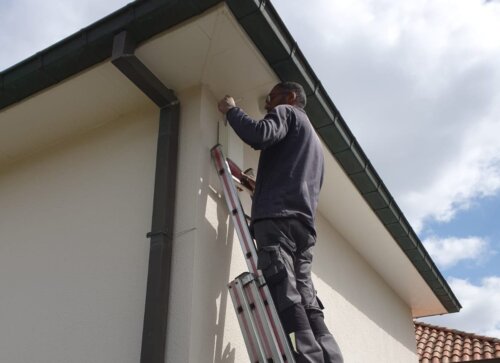 Monteur van Camerainstallatie.nl staat op een ladder en hangt een domecamera op